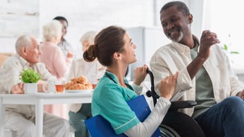 nurse with clipboard talking with man in nursing home