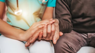female healthcare worker holding hands of senior man
