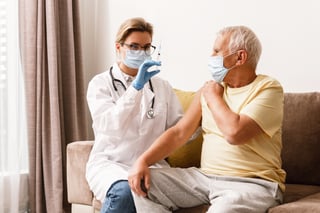 doctor-injecting-vaccine-to-elderly-man-during-hom-2023-07-31-21-39-53-utc