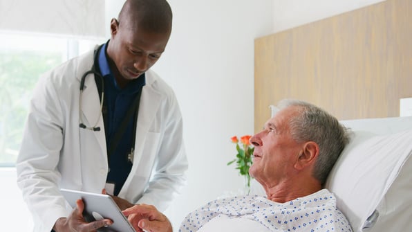 Senior and nurse speaking, looking at a tablet