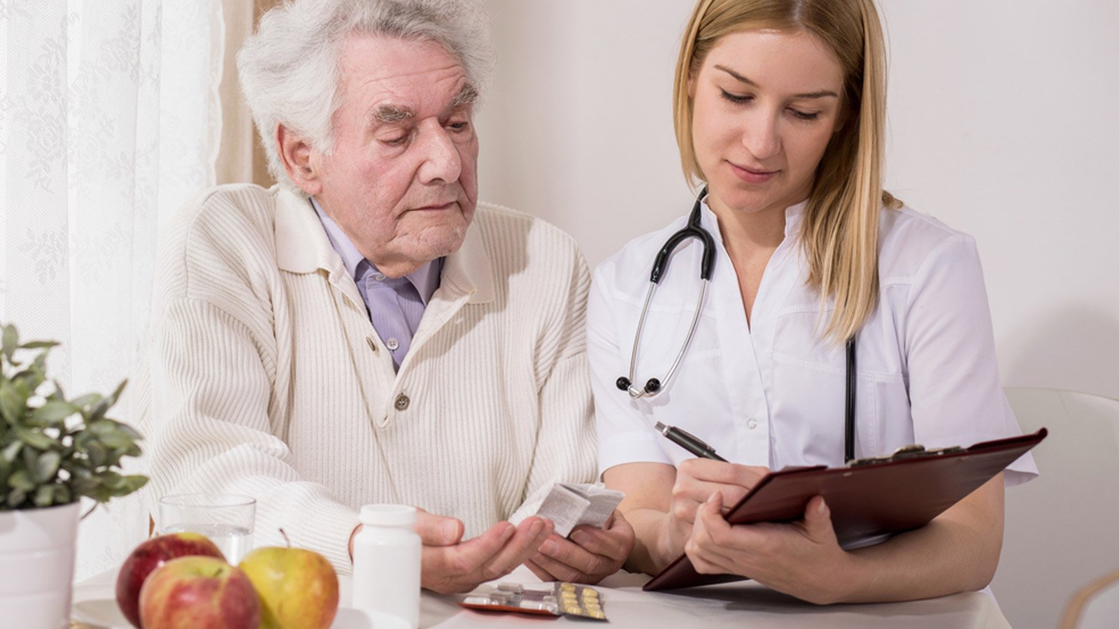 Senior male adult looking at nurse's clipboard