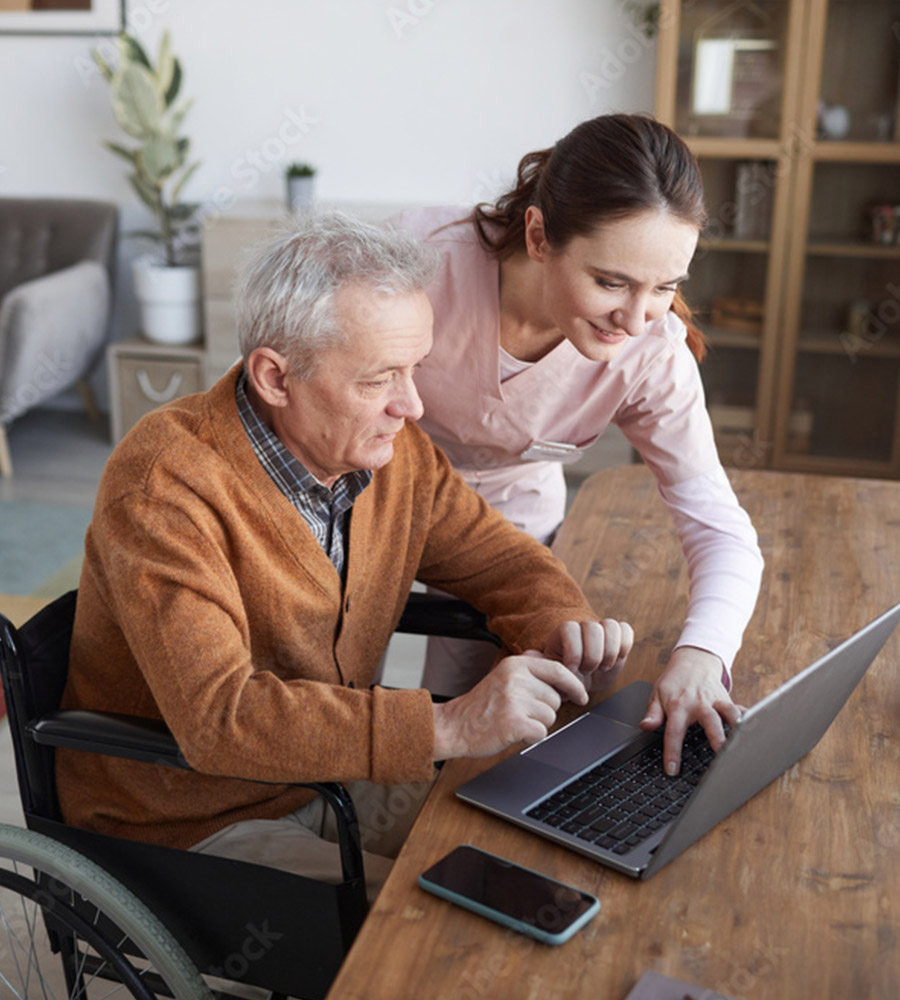 nurse helping elderly man on laptop