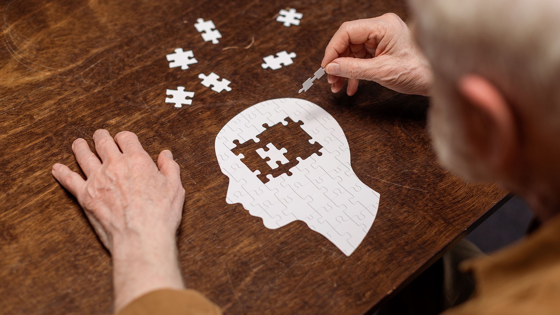 Overhead view of man putting together puzzle of brains representing alzheimers