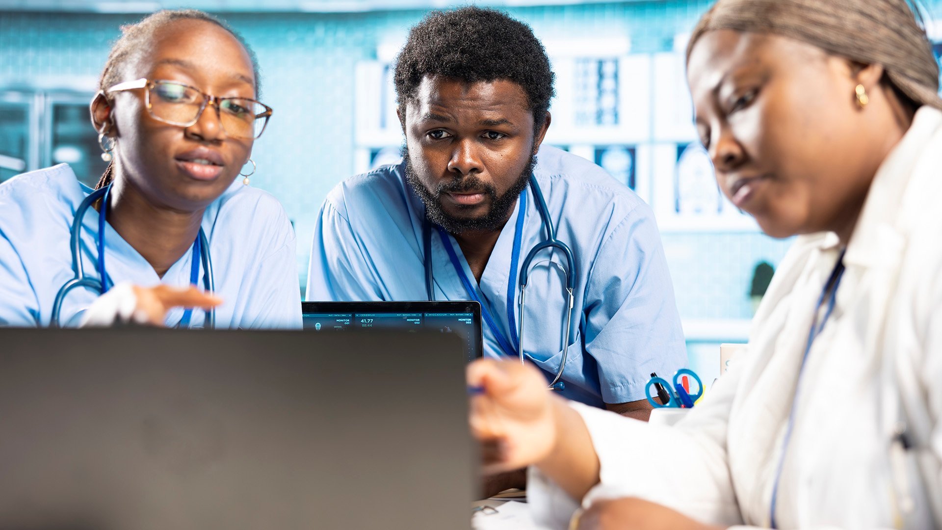 Group of nurses reviewing documents on a laptop