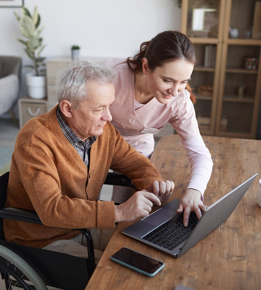 nurse with elderly man on laptop