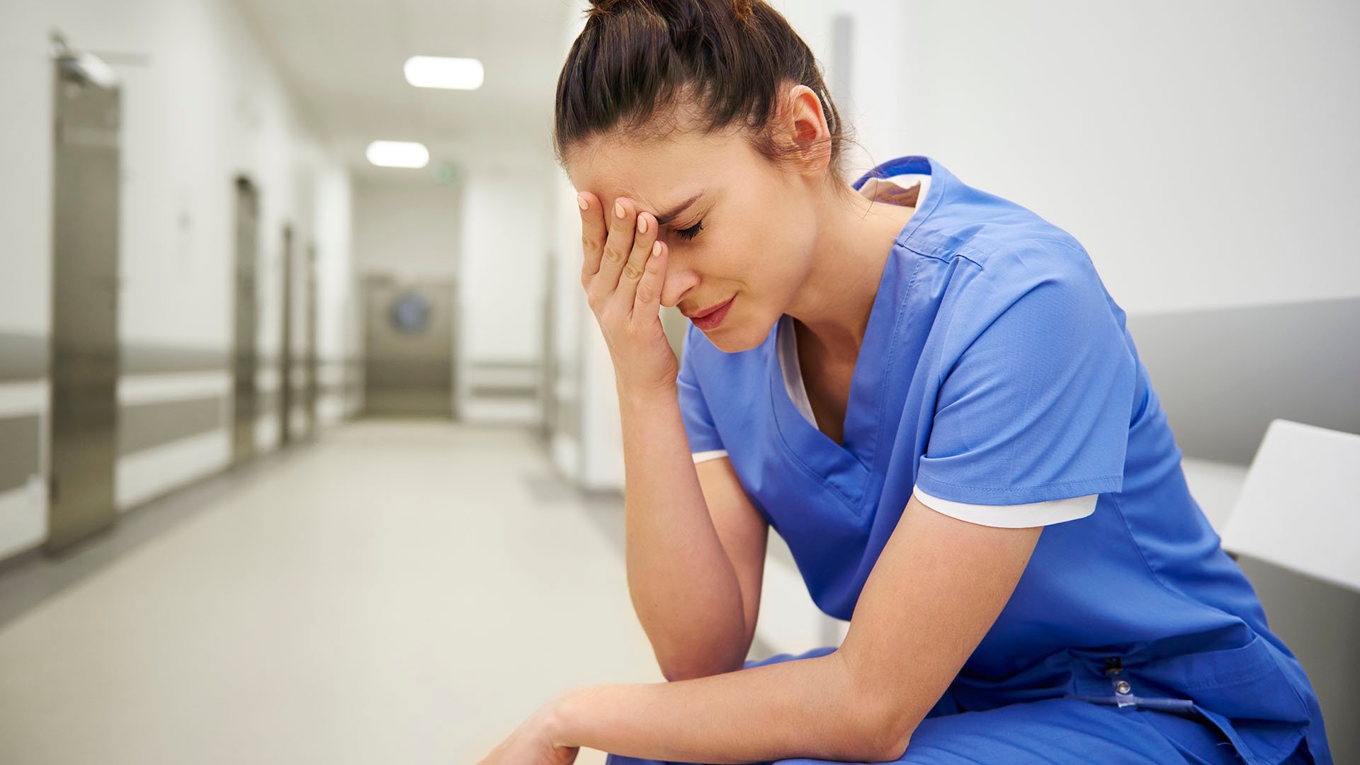 A distraught nurse in a hallway representing stress awareness month